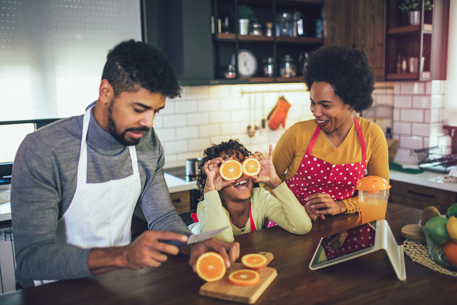 Family Using Gadgets Whilst Eating Breakfast Together In Kitchen