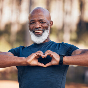 African American man smiling at camera with hands in shape of heart in front of chest