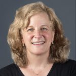 A headshot of a white woman wearing a black t-shirt