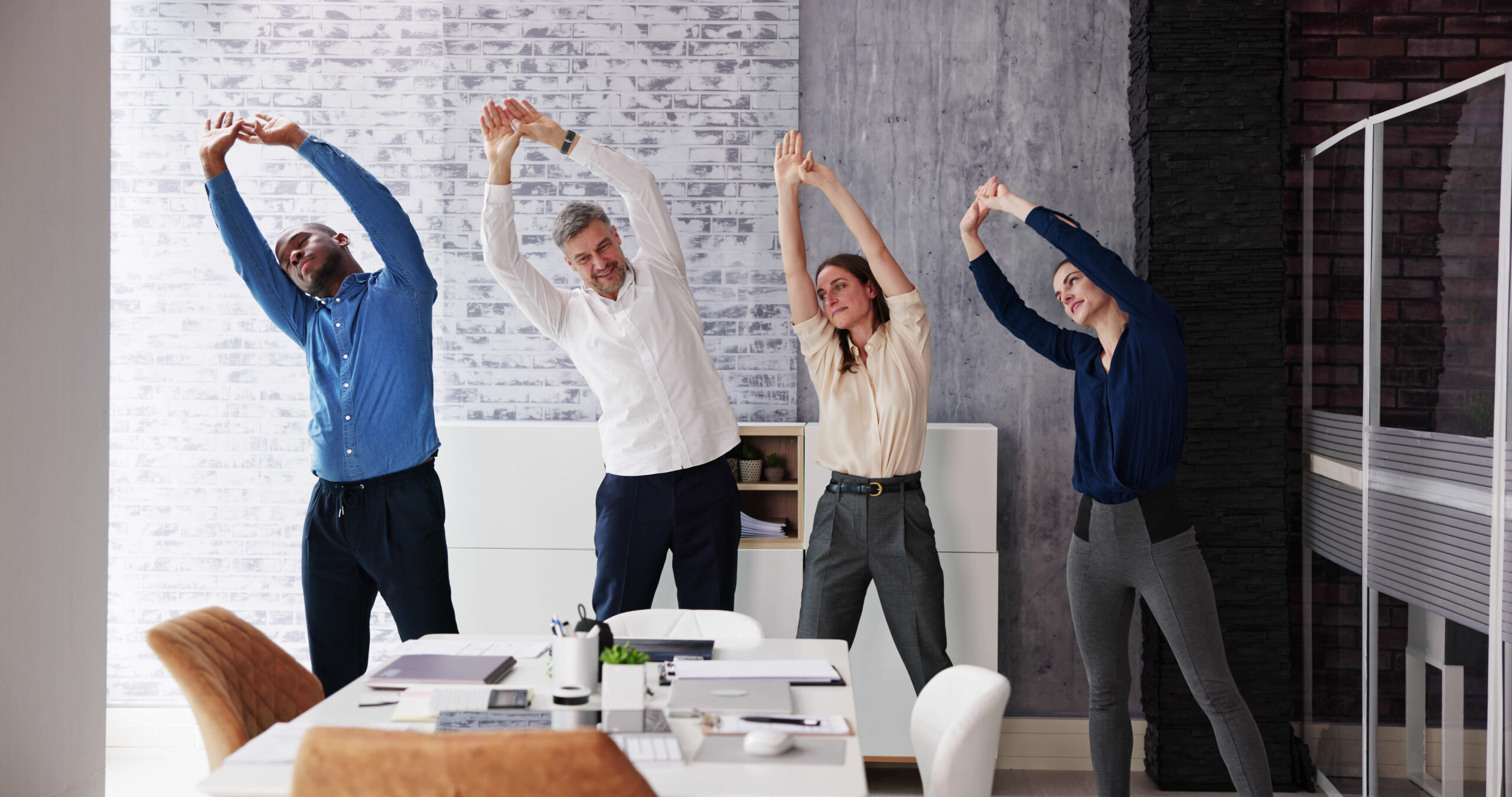 four colleagues stretching in office together