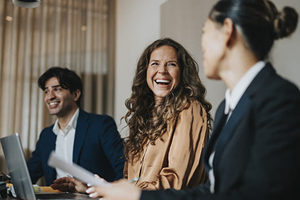 Colleagues laughing with laptops open