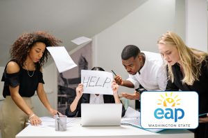 group of people surrounding a person sitting down, while they are holding up a piece of paper with "help" written on it.