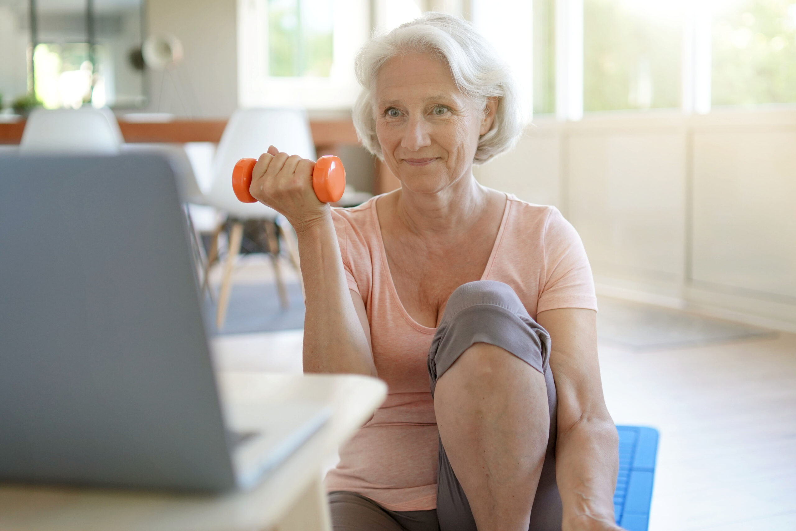 woman lifting small dumbbell watching computer