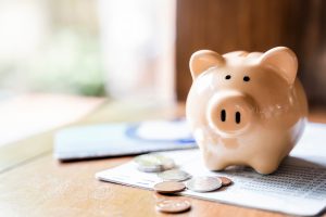 Piggy bank with coins and saving book bank on wooden table