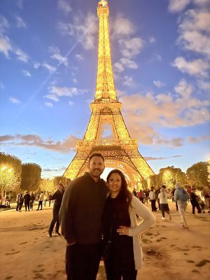 Two people standing in front of the Eiffel Tower in Paris at disk. 