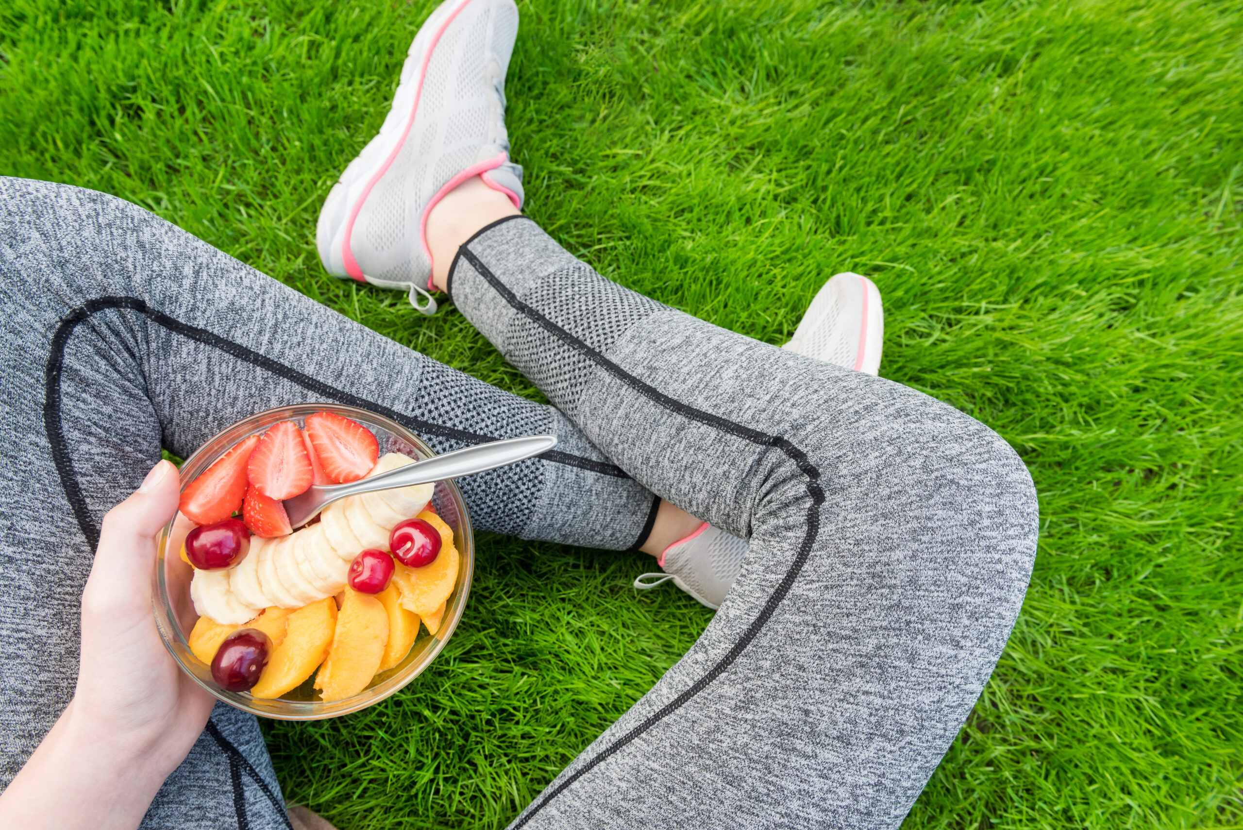 yogurt and fruit bowl in hands of girl with athletic clothing on