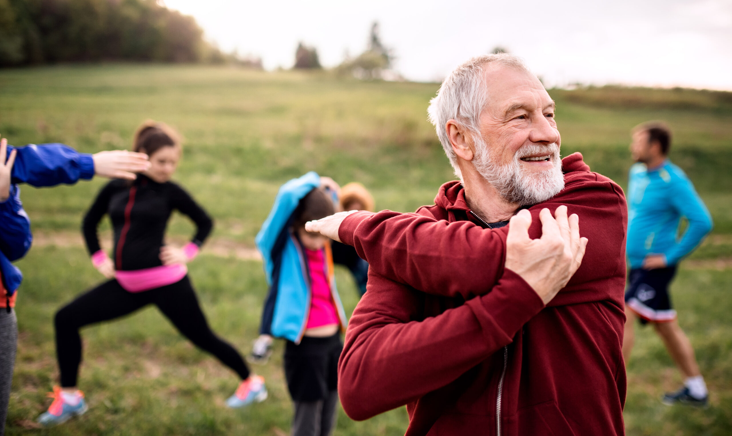 man stretching with running group outside and smiling