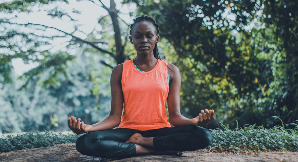 Women sitting crossed legged on the floor in a meditative pose.