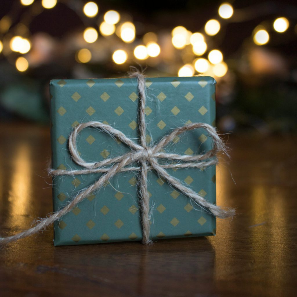 hand wrapped present underneath a christmas tree.